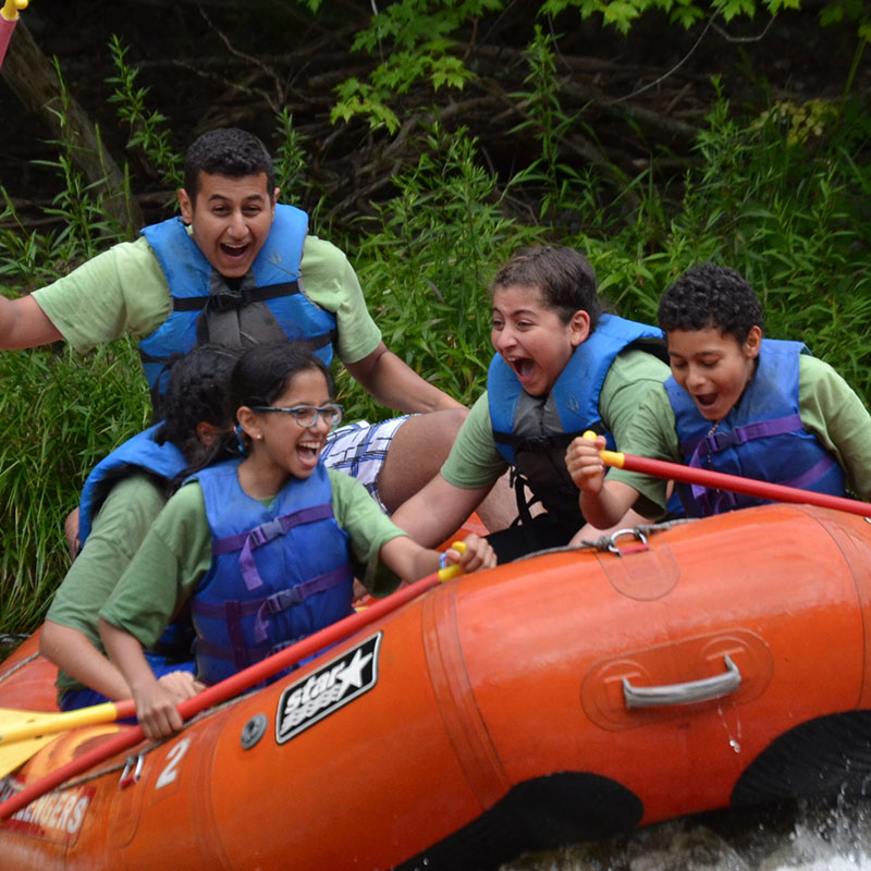 A group whitewater rafting and smiling